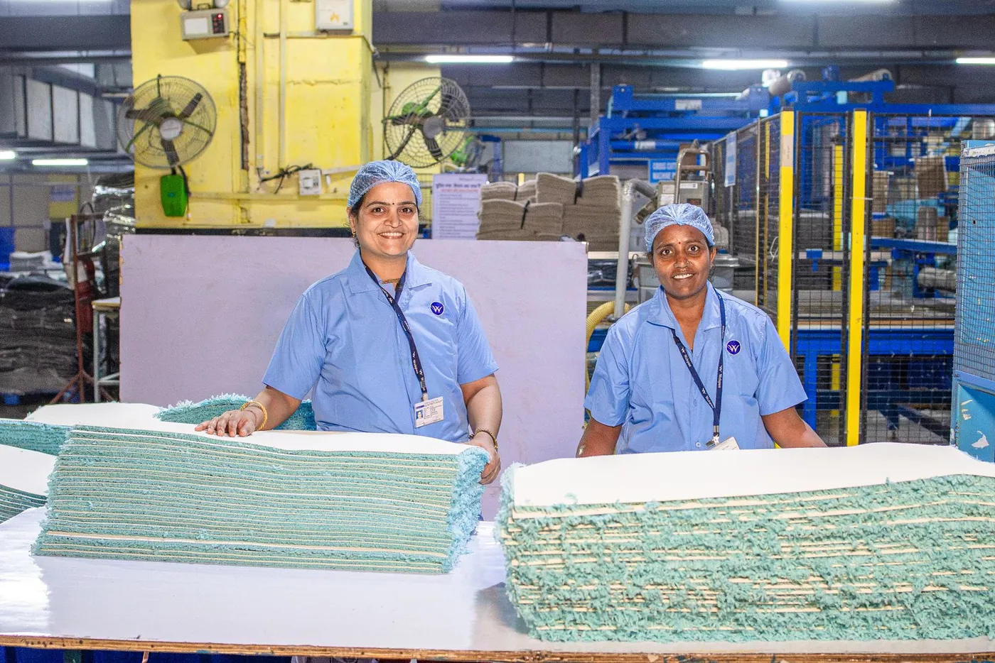 Two factory workers beside finished goods
